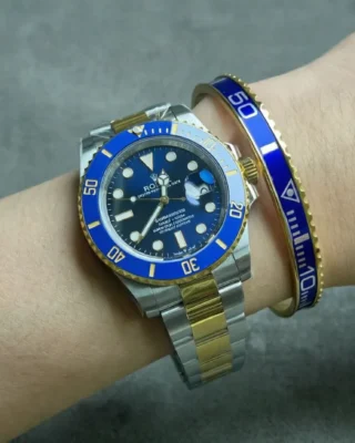 Close-up of Bluesy Blue Submariner watch with rich blue dial and bezel on a man's wrist, premium gold tone bracelet