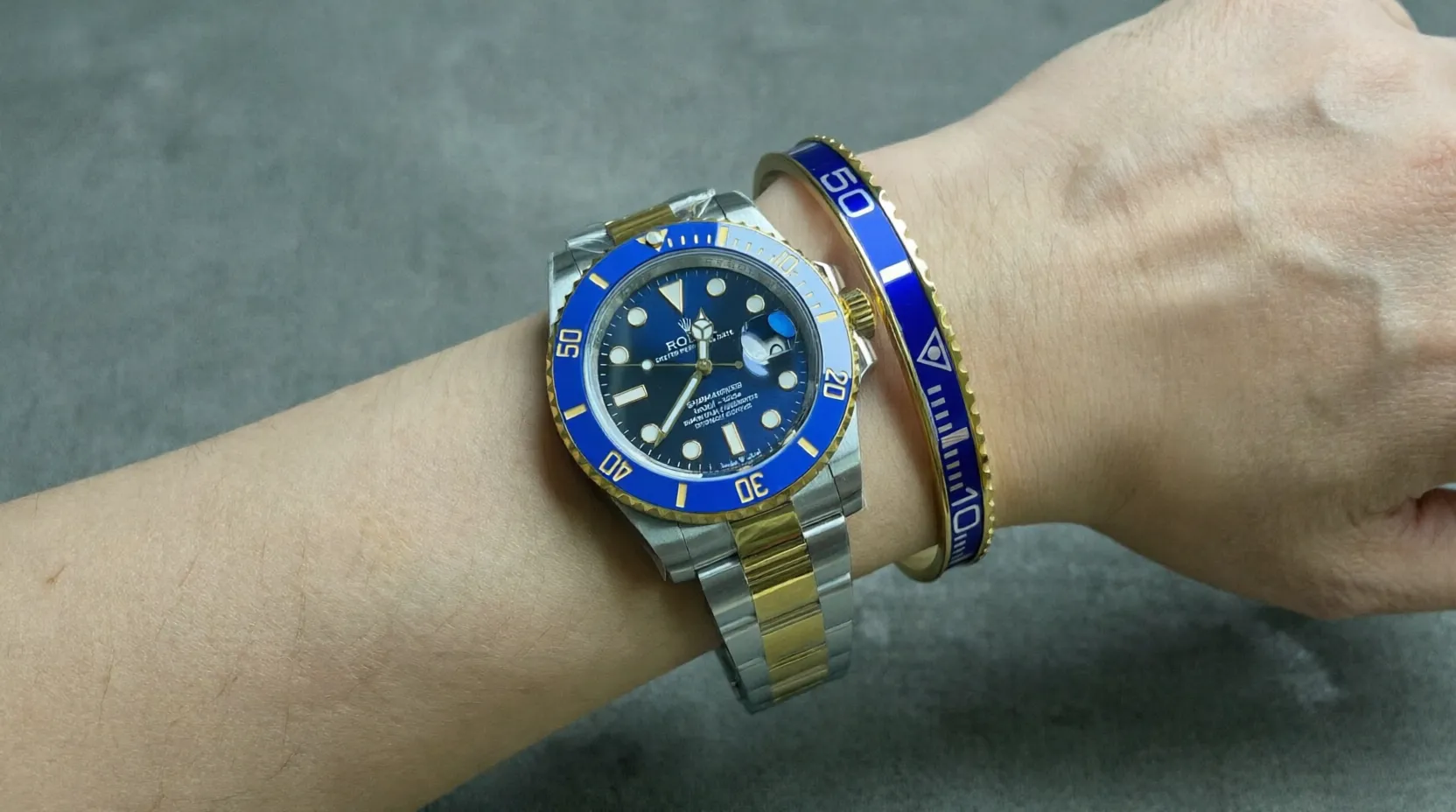 Close-up of Bluesy Blue Submariner watch with rich blue dial and bezel on a man's wrist, premium gold tone bracelet