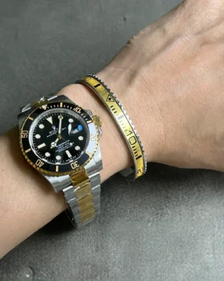 Close-up of Submariner Black Dial 126613LN watch with bright yellow bezel on a man's wrist, premium titanium steel bracelet