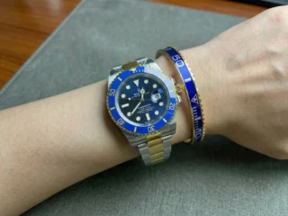 Close-up of a wrist wearing a sleek Blue Submariner Gold Tone Bracelet perfectly paired with a Rolex Submariner watch.