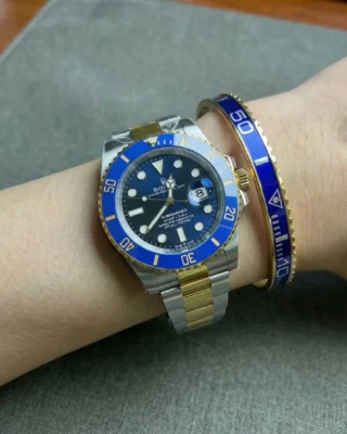 Close-up of a wrist wearing a sleek Blue Submariner Gold Tone Bracelet perfectly paired with a Rolex Submariner watch.