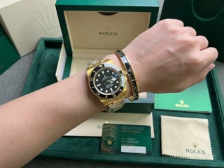 Close-up of a wrist wearing a sleek Black Submariner Gold Tone Bracelet perfectly paired with a Rolex Submariner watch.