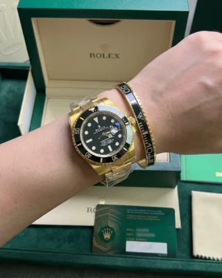 Close-up of a wrist wearing a sleek Black Submariner Gold Tone Bracelet perfectly paired with a Rolex Submariner watch.